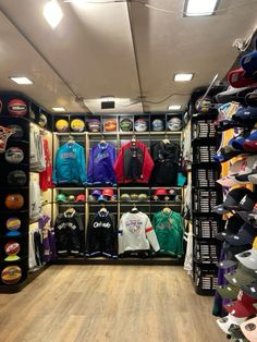 the inside of a clothing store with lots of shirts and hats on display in it