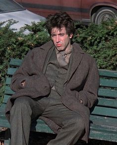 a man sitting on top of a green bench