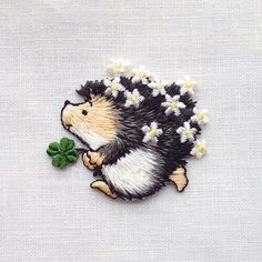 an embroidered hedge with daisies on it's back, sitting next to a clover