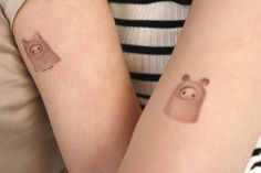 two people with matching tattoos on their arms, one has a bear and the other has a pig