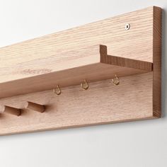 a wooden coat rack with three hooks and two rings hanging from it's sides