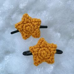 two crocheted yellow stars sitting on top of snow