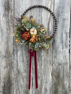 a wreath is hanging on the side of a wooden wall with leaves and flowers in it