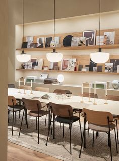 a long table with many chairs and pictures on the wall behind it in a room