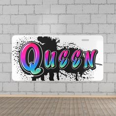 the word queen painted on a white license plate in front of a brick wall and floor