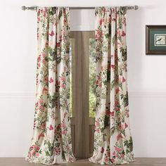 an open window with floral curtains in front of white walls and wood flooring on the side