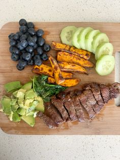 a wooden cutting board topped with meat and veggies