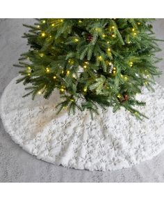 a small christmas tree with lights on it and a white rug in front of it