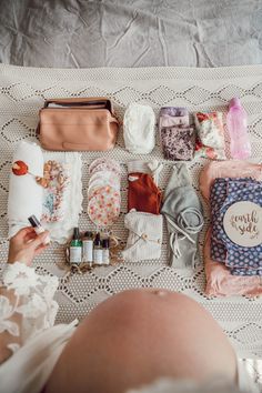 a woman laying on top of a bed covered in lots of different types of items