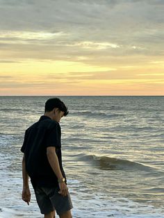 a man standing on top of a sandy beach next to the ocean