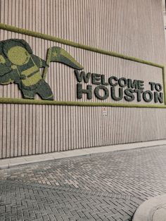 a skateboarder is doing a trick in front of a welcome to houston sign