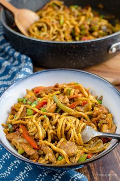 two bowls filled with noodles and vegetables on top of a wooden table