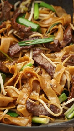 stir fried noodles with beef and vegetables in a wok