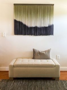 a living room with a couch, rug and painting on the wall above it's headboard