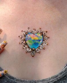 a woman's stomach with a colorful heart shaped brooch on the back of her chest