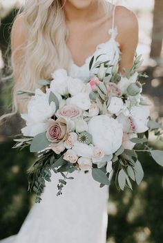 a bride holding a bouquet of white and pink flowers