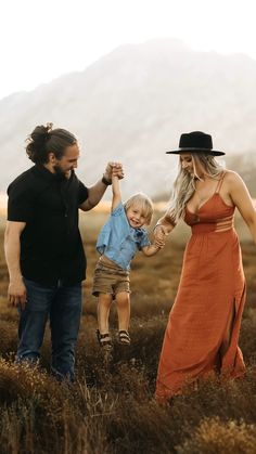 a man, woman and child holding hands in a field