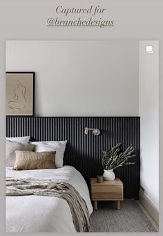 a white bed sitting next to a wooden night stand