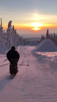 a man riding skis down the side of a snow covered slope under a sunset