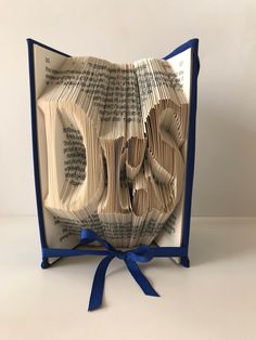 an open book with pages folded into the shape of a face and blue ribbon tied around it