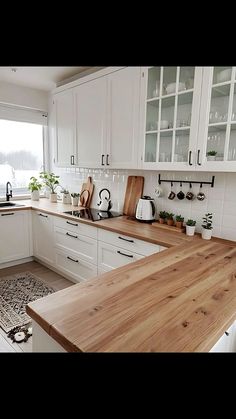 a kitchen with white cabinets and wooden counter tops in front of a large open window