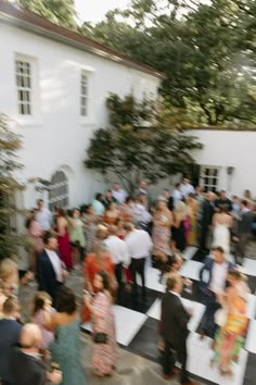 a group of people standing around in front of a white building with lots of windows