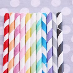 six different colored striped straws lined up in a row on a polka dot background