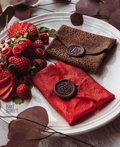 some strawberries and chocolate are on a plate with red napkins next to it