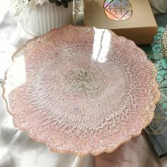 a pink plate sitting on top of a table next to a box and some flowers