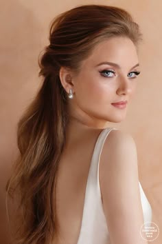 a woman with long brown hair and blue eyes is looking at the camera while wearing white dress