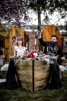 a man and woman sitting at a table with candles in their hands, dressed in medieval garb