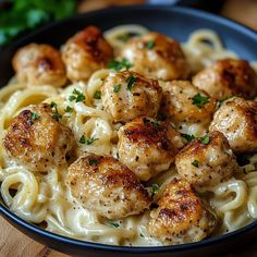 pasta with meatballs and parsley in a black bowl on a wooden table top