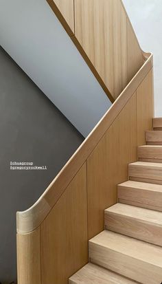 a wooden stair case next to a gray wall