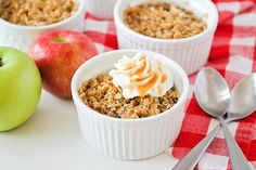 three small white bowls filled with oatmeal next to an apple and spoon