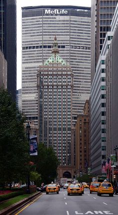 taxi cabs are driving down the street in front of tall buildings and skyscrapers