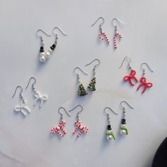 several pairs of earrings with bows and beads are shown on a white surface, next to a pair of scissors