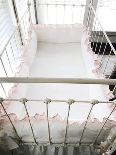 a white crib with pink ruffled trim