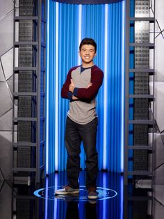 the young man is standing in front of a blue wall and posing for a photo