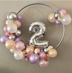 the number two is made out of balloons and flowers on a circular metal ring with a balloon garland attached to it