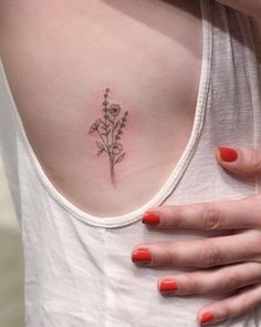 a woman's chest with a small flower tattoo on the left side of her stomach