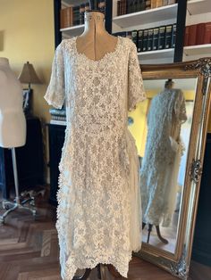 a white dress is on display in front of a mirror and some bookshelves