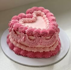 a heart shaped cake sitting on top of a white plate with pink icing in the shape of a heart