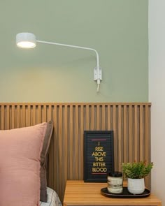 a bed with a pink pillow on top of it next to a night stand and lamp