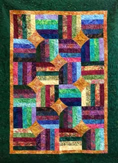 a quilted wall hanging on the side of a green wall with multicolored squares