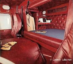 the interior of a vehicle with red leather upholstered bedding and headboard