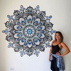 a woman standing in front of a wall with a blue and white flower design on it