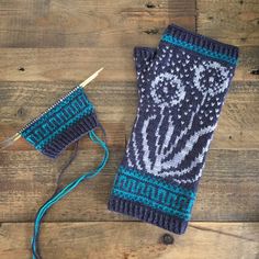 two knitted mitts sitting on top of a wooden floor next to a pair of scissors