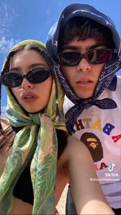 a man and woman taking a selfie on the beach with sunglasses on their heads