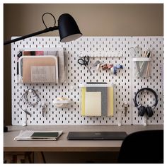 an office desk with various items on it and a black lamp hanging from the wall