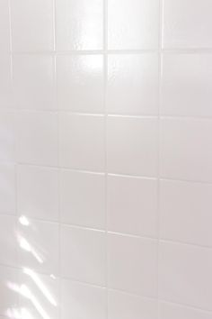 a white tiled bathroom wall and floor